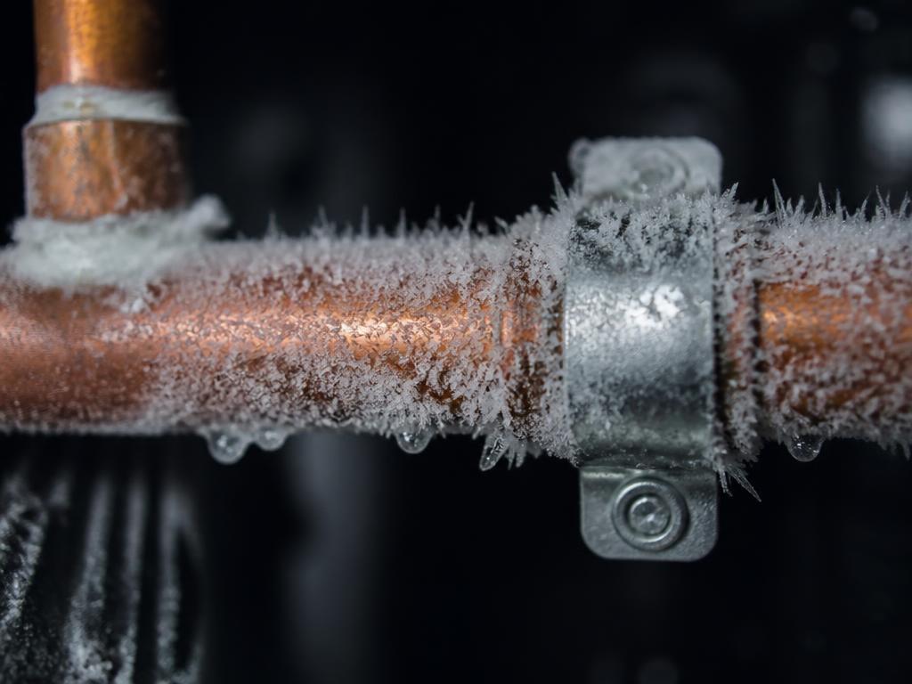Frost and ice crystals formed on a section of copper pipe during pipe freezing